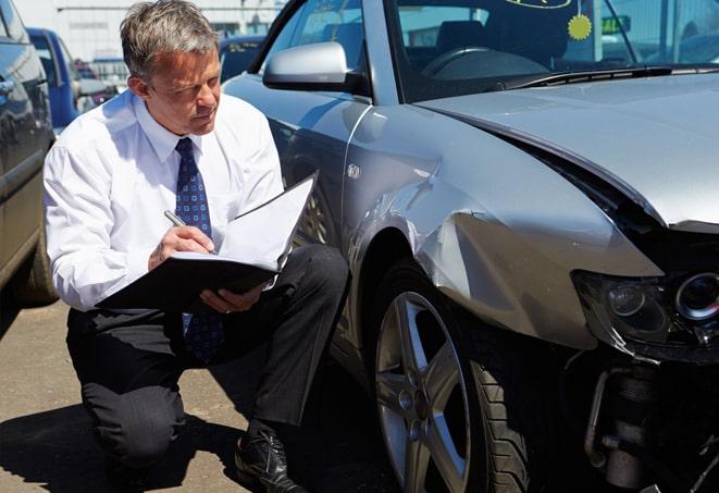 green car with insurance paperwork and keys on a desk